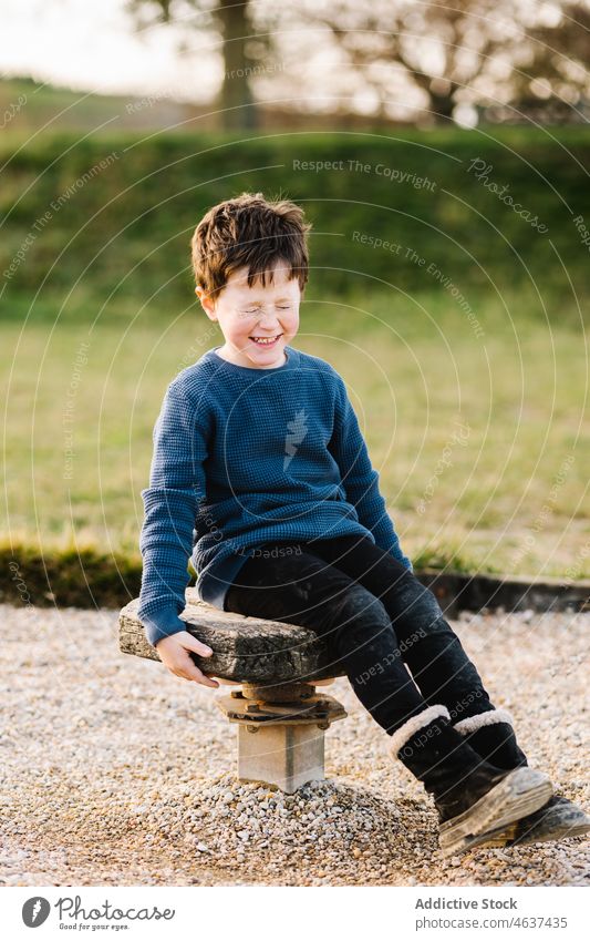 Cheerful boy on wooden platform kid playground having fun entertain eyes closed childhood amusement playful summer pastime leisure recreation cute innocent