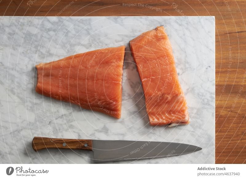 Raw fish on cutting marble board salmon raw fillet food ingredient kitchen cook culinary cuisine knife seasoning slate recipe seafood prepare uncooked spoon