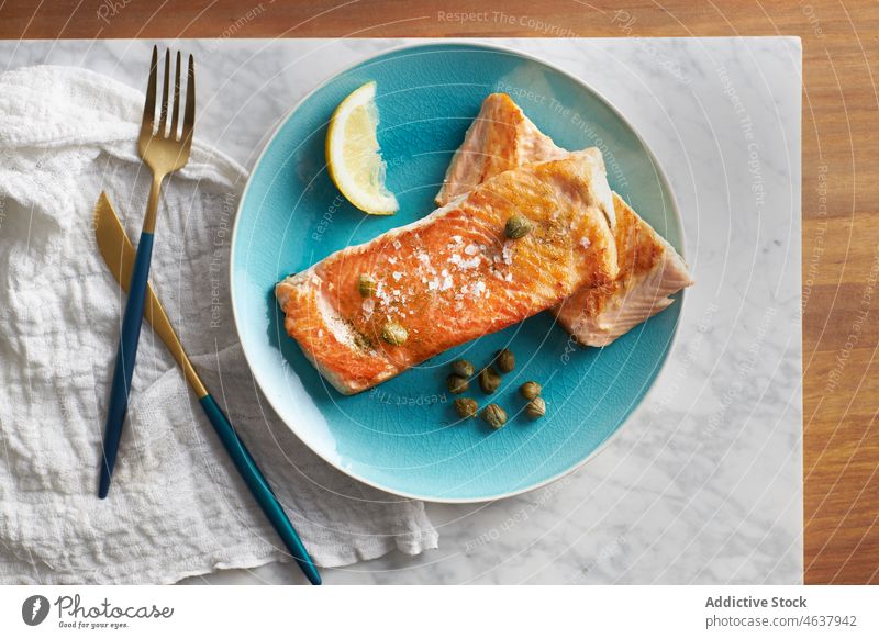 Delicious baked fish fillet with lemon salmon food steak seafood serve culinary cuisine eat dish plate meal dinner knife slice delicious tasty fork gourmet