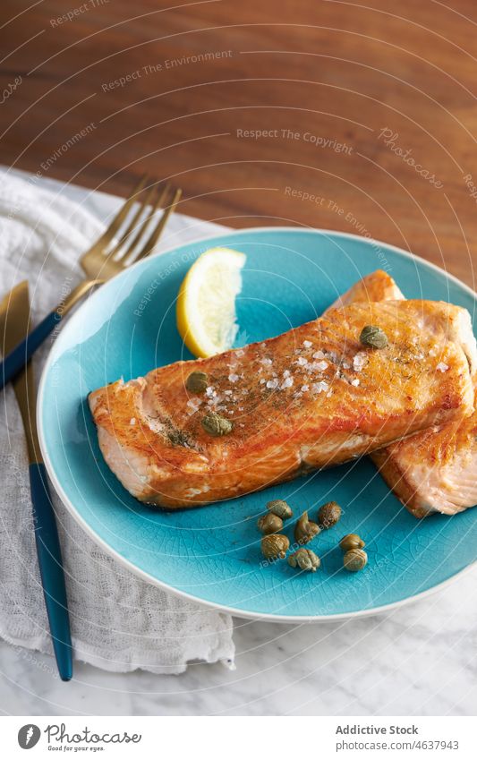 Delicious baked fish fillet with lemon salmon food steak seafood serve culinary cuisine eat dish plate meal dinner knife slice delicious tasty fork gourmet