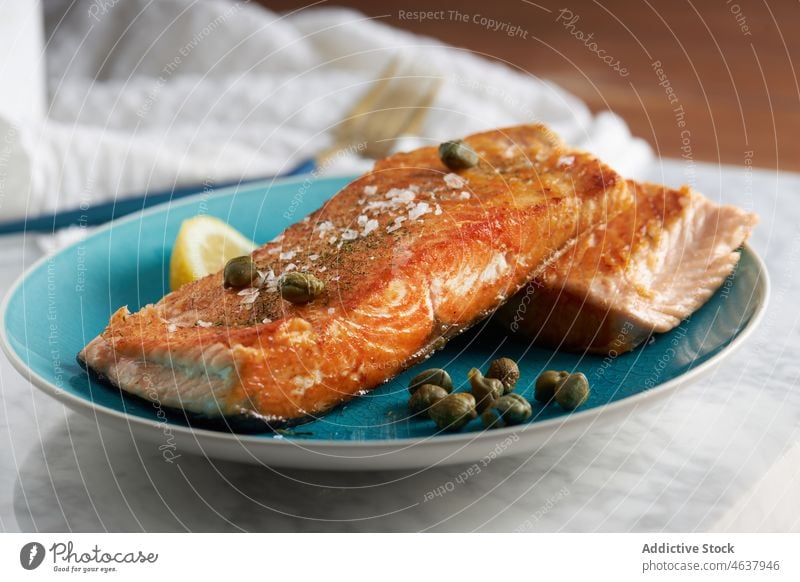 Delicious baked fish fillet with lemon salmon food steak seafood serve culinary cuisine eat dish plate meal dinner knife slice delicious tasty fork gourmet