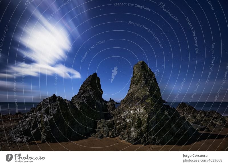 Kilfarrasy Strand night photography. Copper Coast of Waterford, Ireland. world geopark by unesco. impressive rocks at night with moon behind some clouds.