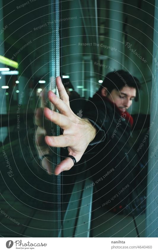 Young man alone in a bus station at night loneliness urban lost depression sad sadness broken broke up forget forgotten mood blue reflection glass crystal