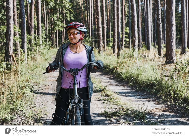 Active woman cycling on forest road. Female riding bicycle off-road route on summer vacation day trip adventure biking recreation travel bike action activity