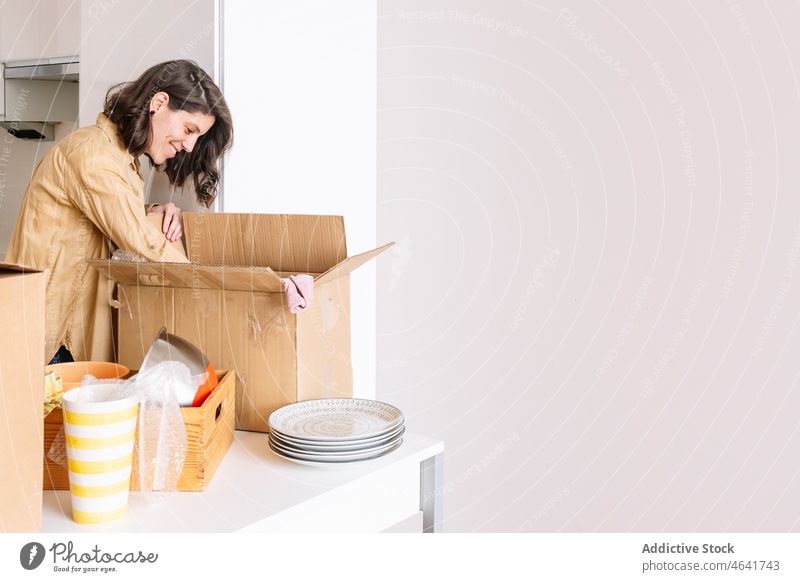 Woman unpacking carton box on floor woman move in apartment kitchen belonging table open female package new dwell residential homeowner mortgage property