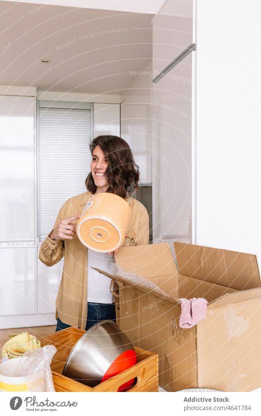 Woman unpacking carton box on floor woman move in apartment kitchen belonging table open female package new dwell pot residential homeowner mortgage property