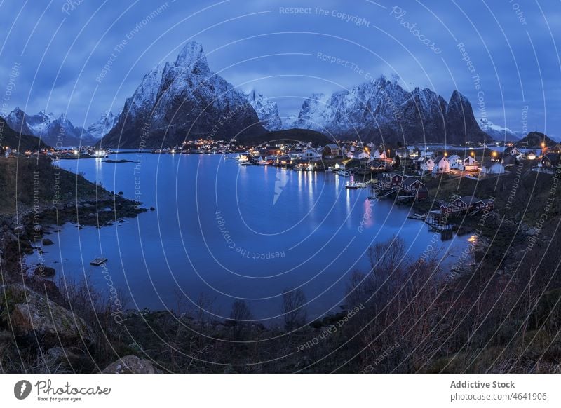 Amazing view of snowy mountains and village located at bottom range settlement house sunset highland landscape picturesque lofoten island norway reine hill