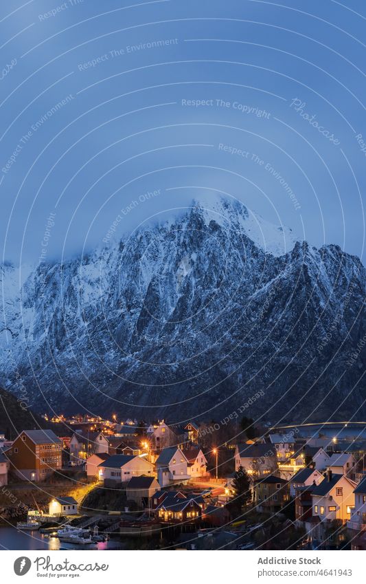 Amazing view of snowy mountains and village located at bottom range settlement house sunset highland landscape picturesque lofoten island norway reine hill