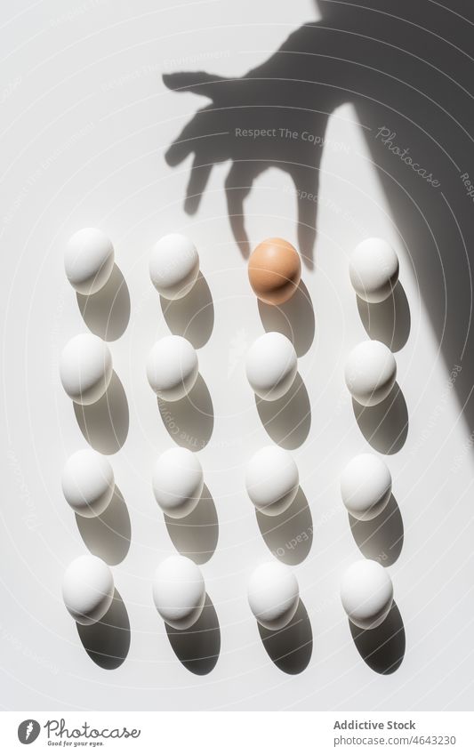 Easter white eggs pattern On A White Background With Shadows. One is brown and different from the others group sphere three-dimensional abstract ball concept