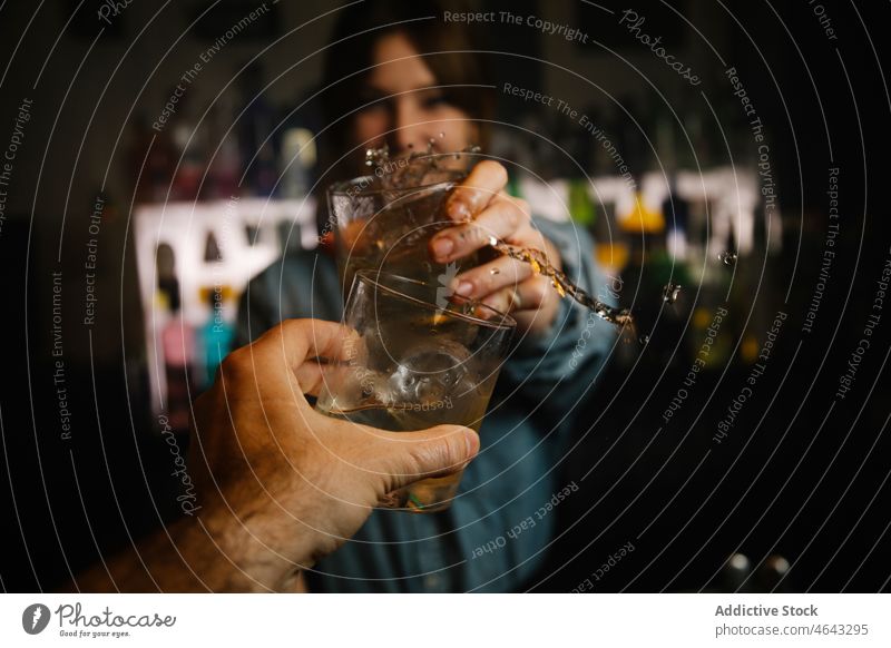 Bartender clinking glasses of cocktails with faceless man woman bartender beverage alcohol toast splash serve booze work counter concentrate pub female drink