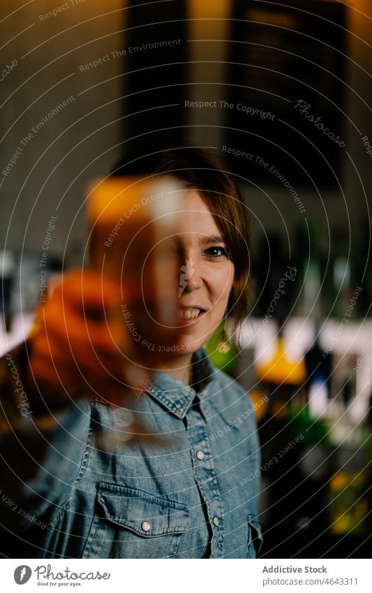 Woman serving gin and tonic cocktail in bar woman bartender beverage alcohol serve booze zest citrus happy orange counter smile glass concentrate work pub