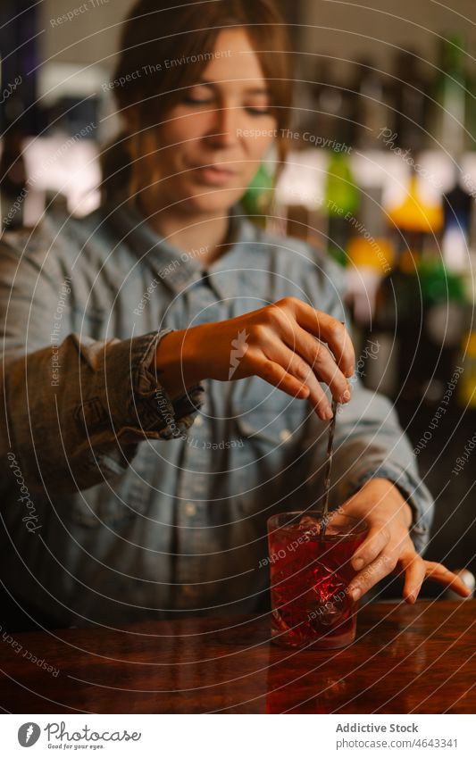 Bartender preparing cocktail in bar woman bartender old fashioned mix beverage alcohol serve booze work counter ice cube cold glass concentrate pub female drink