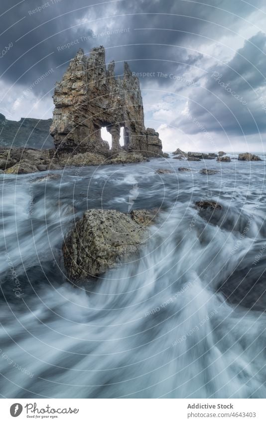 Rocky formations in flowing sea rock cliff water nature stone mountain rocky sundown seawater asturias spain rough cloudy environment scenery uneven marine