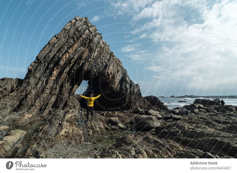 Anonymous traveler near rock on shore trip adventure beach cliff sea water coast nature stone asturias spain formation rough cloudy cudillero rocky environment