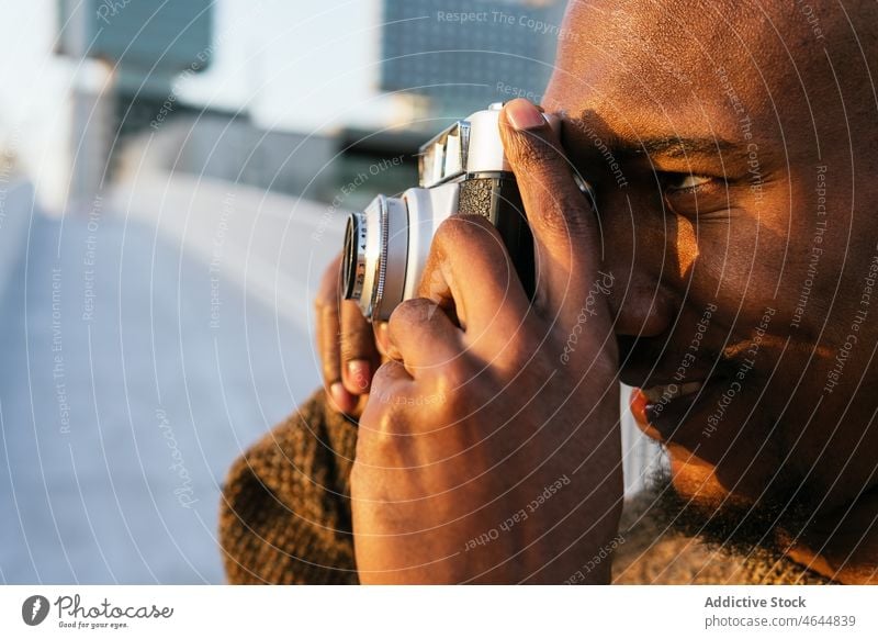 Smiling black man taking photo on street photo camera photographer take photo cheerful photography smile hobby capture pastime lawn city male bald