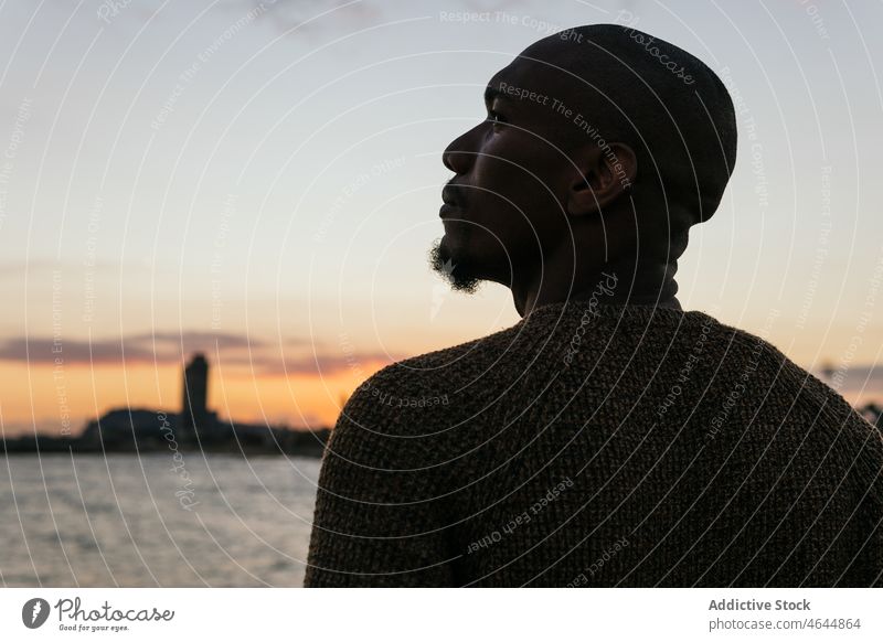 Man standing on seashore at sunset time man embankment enjoy admire evening waterfront coast male silhouette bald unshaven guy town summer beach seaside