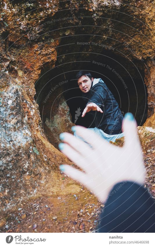 Young man get in into a dark cave adventure explore speleology spelunking back inside brave adventurer alone lonely lonelyness solitude help back view young