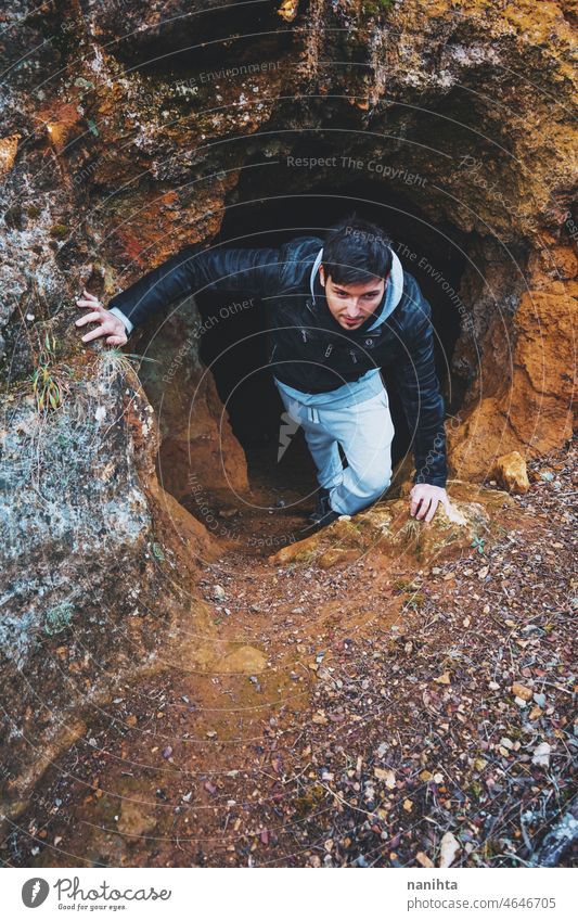 Young man get in into a dark cave adventure explore speleology spelunking back inside brave adventurer alone lonely lonelyness solitude help back view young