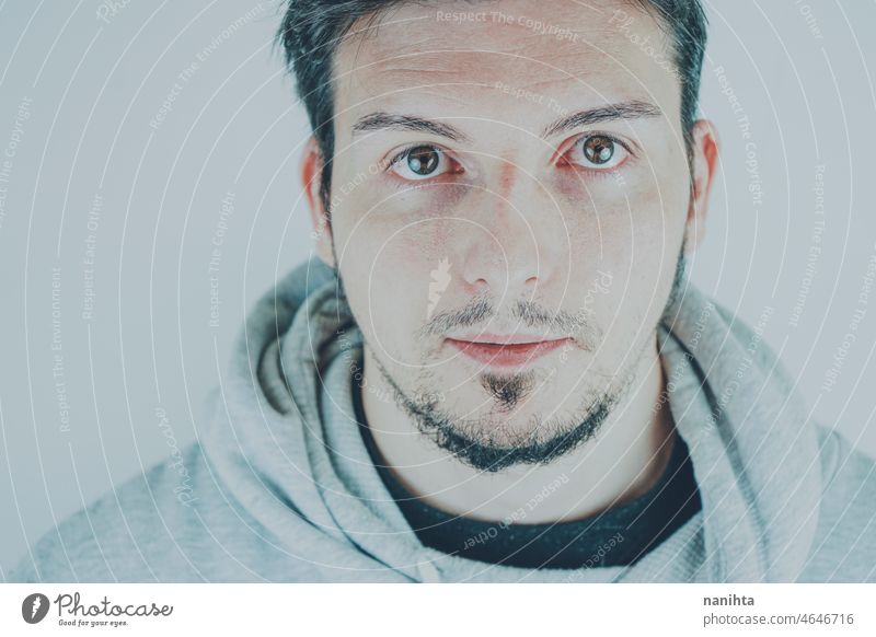 Portrait of a handsome young man against white background male portrait studio expression face mood moody guy eyes look close close up beard brunette black hair