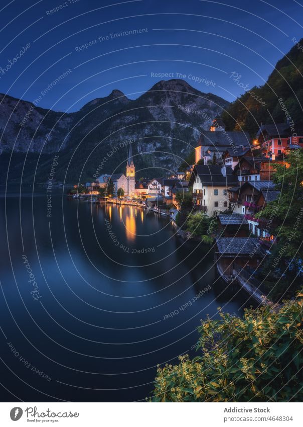 Hallstatt settlement near calm river village residential building water mountain nature riverside forest rock woodland stone night range ridge majestic typical