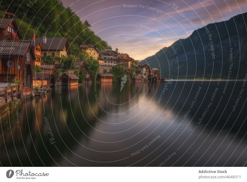 Hallstatt city near calm river settlement village residential building water mountain nature riverside forest rock woodland stone range ridge majestic