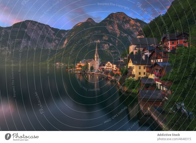 Hallstatt city near calm river settlement village residential building water mountain nature riverside forest rock woodland stone range ridge majestic