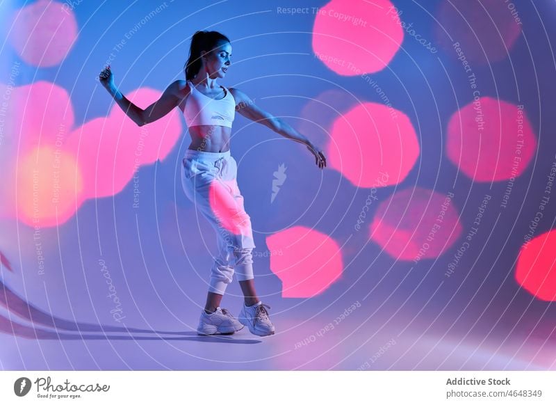 Graceful woman in white studio with bright lights dancer gentle move grace bokeh illuminate perform female model eyes closed sportswear flexible sporty