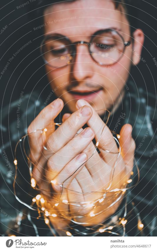 Young man holding christmas lights in his hands magic nostalgia male warm holidays vacation winter dark darkness night eve magical delicate fragile new year