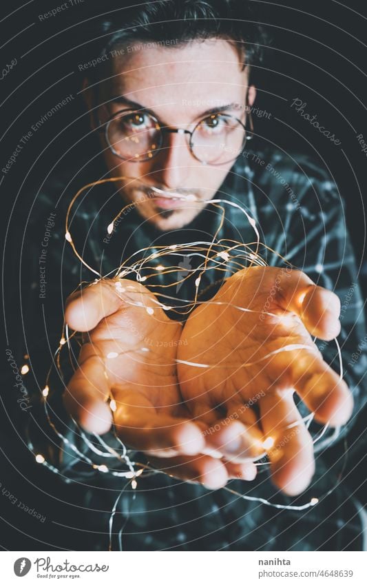 Young man holding christmas lights in his hands magic nostalgia male warm holidays vacation winter dark darkness night eve magical delicate fragile new year