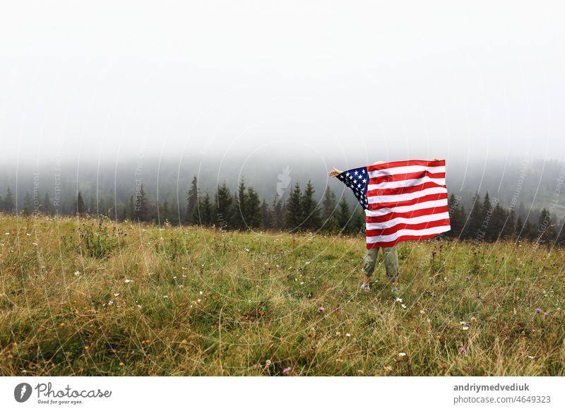 Happy adorable little girl smiling and waving American flag. Patriotic holiday. Happy kid, cute little child girl with American flag. USA celebrate 4th of July. Independence Day concept.