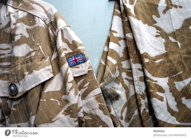 Old military jackets in brown and beige with camouflage pattern and Union Jack on the sleeve in front of an old factory in the Margaretenhütte district of Giessen on the river Lahn in the German state of Hesse