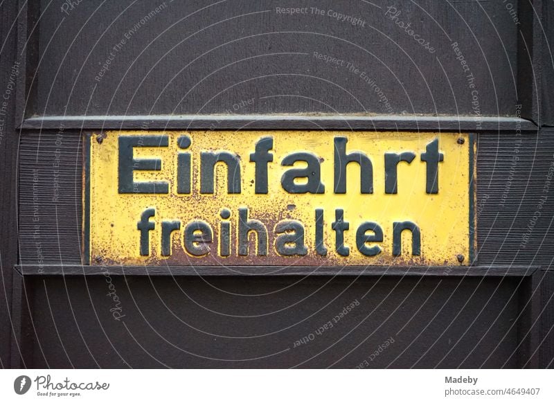 Rusty yellow old tin sign "Keep driveway clear" on a brown wooden gate in Seckbacher Landstraße in the Bornheim district of Frankfurt am Main in the German state of Hesse