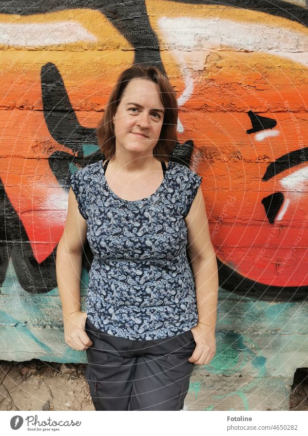 She stands in front of a creatively graffitied wall of a lost place. Woman Feminine Human being Adults Colour photo Exterior shot shirt T-shirt Pants Face Arm