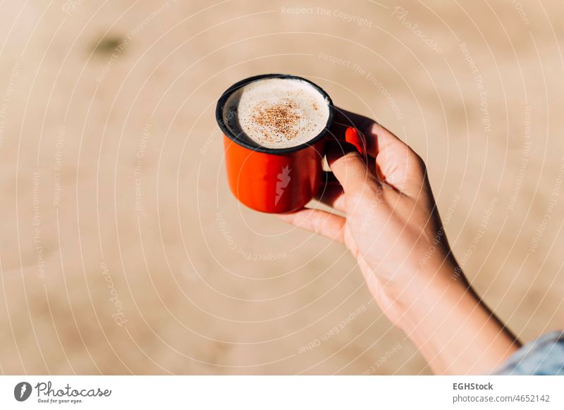 Hand of a woman holding a red enamel cup of coffee with cinnamon and cocoa adult autumn autumnal background break coffee cup comfort comfortable cosy coziness