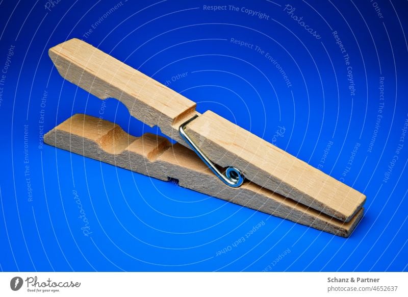geöffnete Wäscheklammer vor blauem Hintergrund einfarbiger Hintergrund freigestellt Krokodil offener Mund Holz Haushalt klemmen