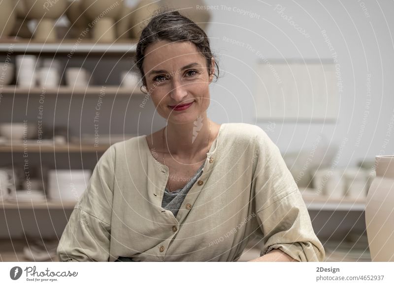 Portrait Of Smiling Mid Adult Potter Sitting In Workshop confidence creativity entrepreneur hairstyle horizontal indoors looking at camera mid adult one person