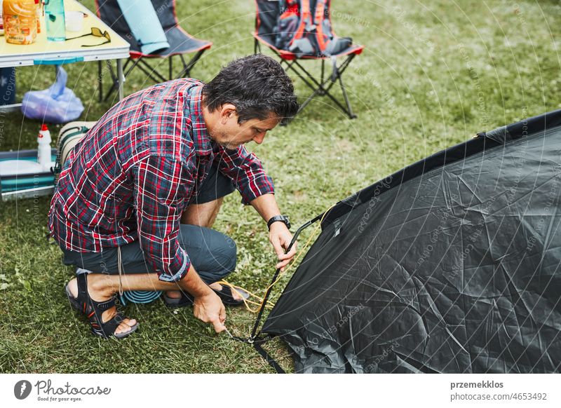 Man putting up a tent at camping during summer vacation. Preparing campsite to rest and relax. Spending vacations outdoors close to nature trip adventure