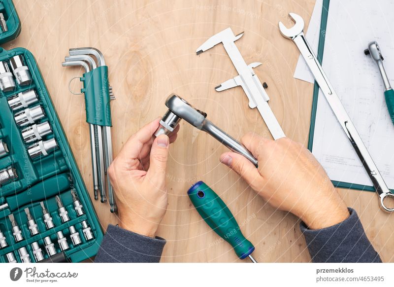 Man working in workshop using many tools. Wrench, spanner, calliper and ratchet with many attachments. Professional equipment repair engineering mechanic