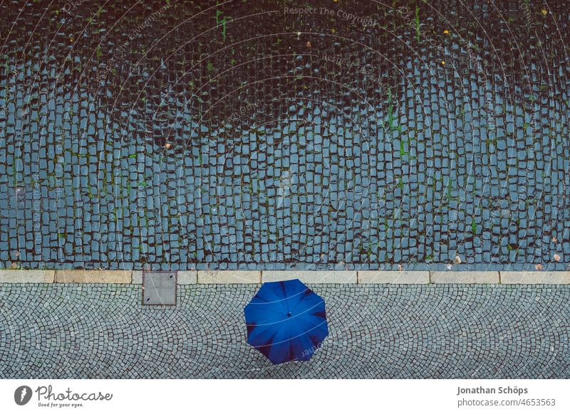 Bird's eye view of person with umbrella on street in rain Bird's-eye view Umbrella Rain Wet Street Paving stone paved Footpath Bad weather Weather rain shelter