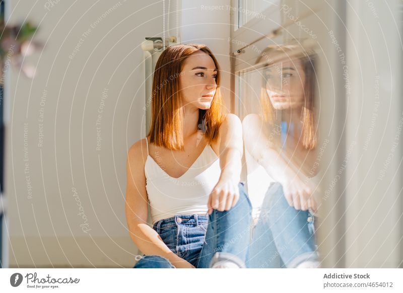 Young woman sitting near window and looking away reflection thoughtful appearance dreamy rest wistful pensive home female young bare shoulders relax ponder