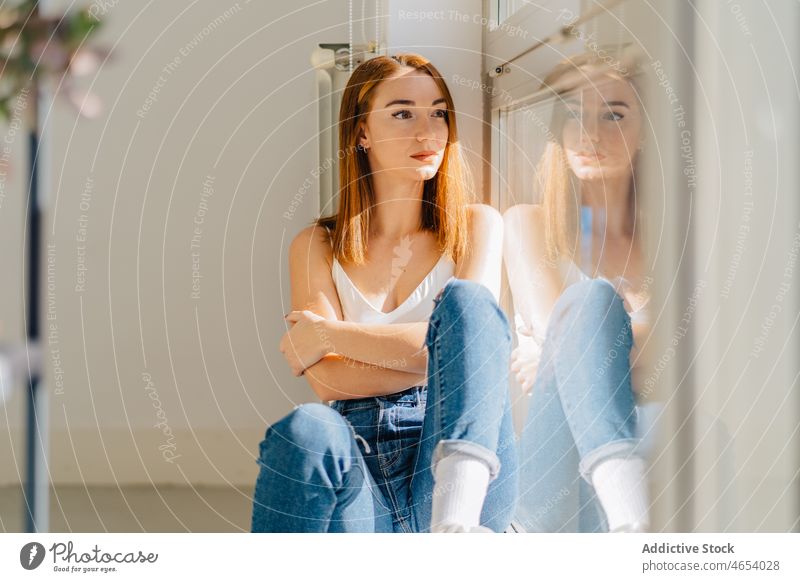 Young woman sitting near window and looking away reflection thoughtful appearance dreamy rest wistful pensive home female young bare shoulders relax ponder