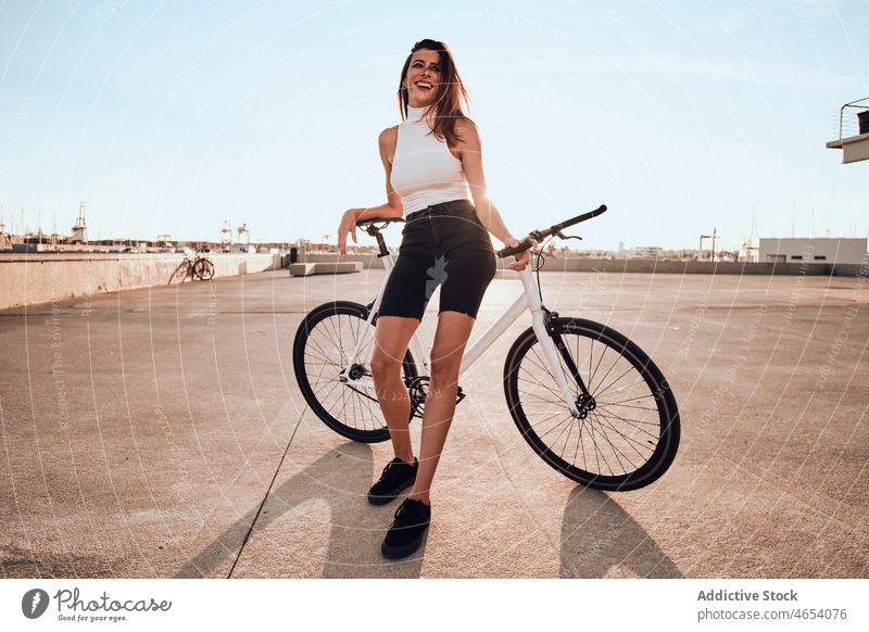 Smiling woman riding bicycle on pavement park activity summer weekend hobby female ride leisure cheerful carefree young smile enjoy street happy free time relax