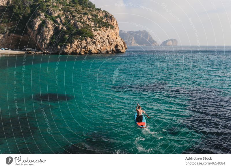 Man practicing paddle surfing on paddleboard with oar on seawater man surfer freedom sup board activity knelling surfboard ocean turquoise aerial azure practice