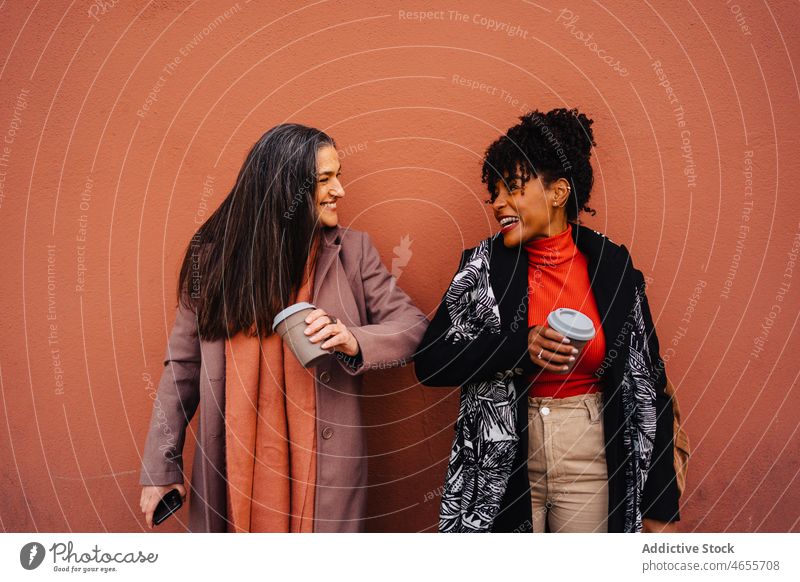 Cheerful diverse ladies with take away coffee cup on red background women friend hot drink using spend time together beverage takeaway smile female best friend