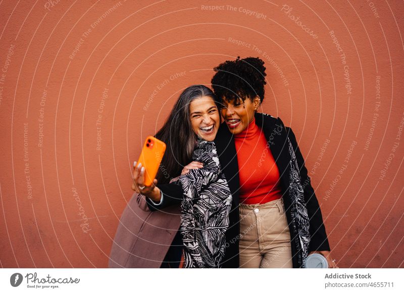 Happy multiracial women taking self portrait on mobile phone friend selfie smartphone cellphone smile together having fun using female best friend spend time