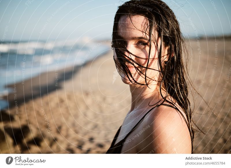 Slim attractive woman standing on sandy beach in sunny day desert summer cloudless seashore blue sky barefoot seaside dress harmony sundress coast wet hair