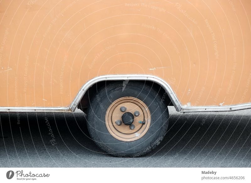 Slightly scratched and dented caravan for camping and vanlife in a warm brown tone in the style of the fifties and sixties with matching steel rim at the Golden Oldies in Wettenberg Krofdorf-Gleiberg near Giessen in Hesse