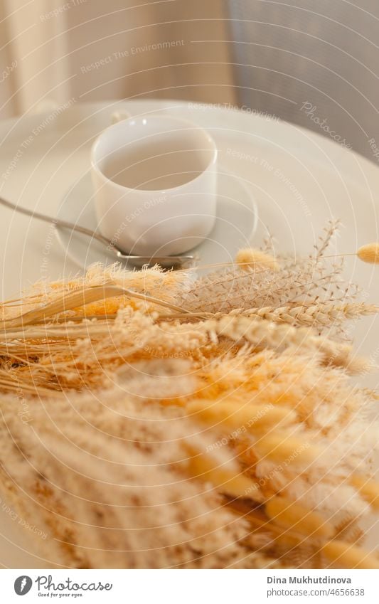 Morning coffee cup with a bouquet of dry flowers and wheat. Breakfast in the morning with coffee and warm sunlight. beautiful cafe flora outdoor blossom drink