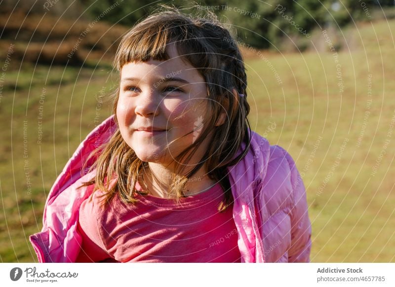 Carefree girl standing in field in autumn meadow sunny enjoy cheerful child kid fall childhood happy cute nature adorable season carefree jacket pink color