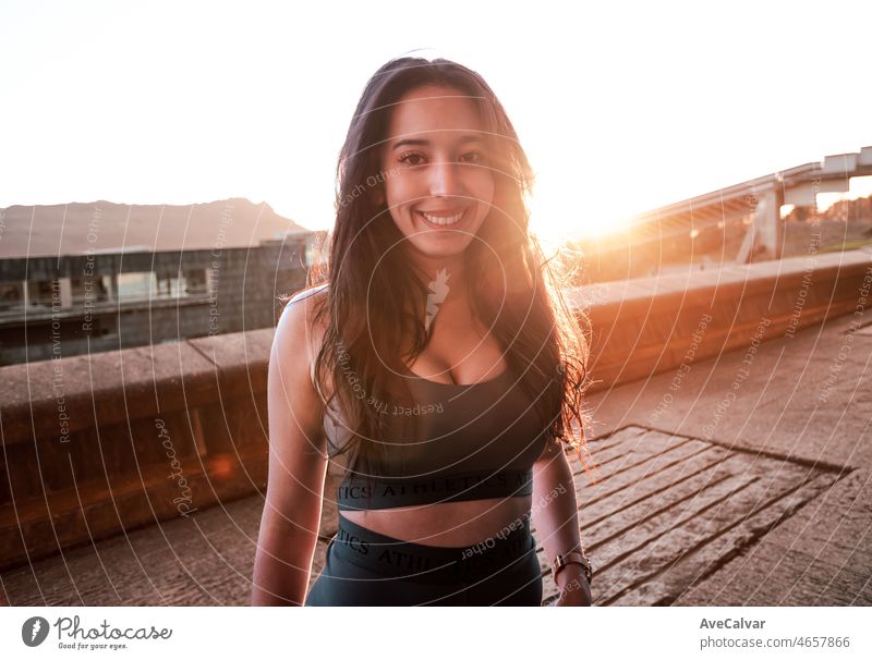 face frontal Young african athlete woman smiling to camera resting during the sunset. Urban space training at the city concept, concrete. Active lifestyle on young people. Training with friends is fun